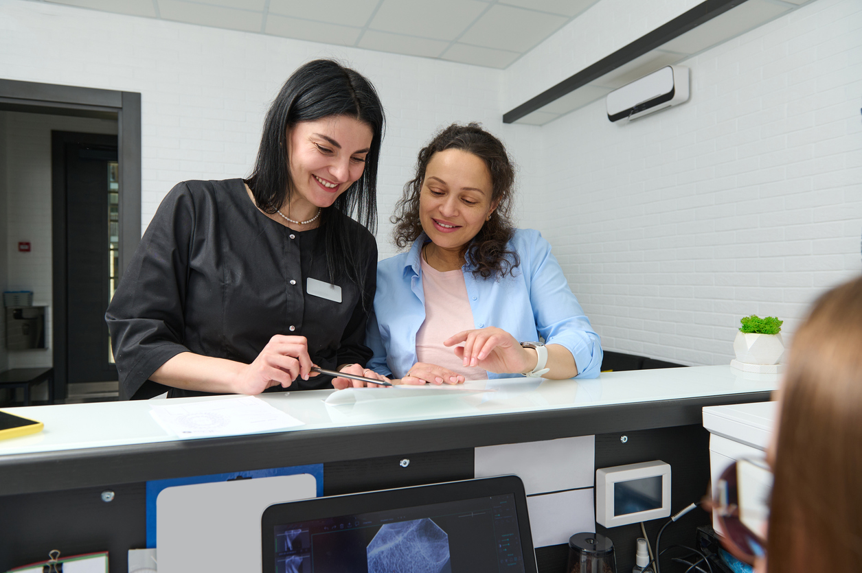Two health care managers review a document in a hospital reception area.