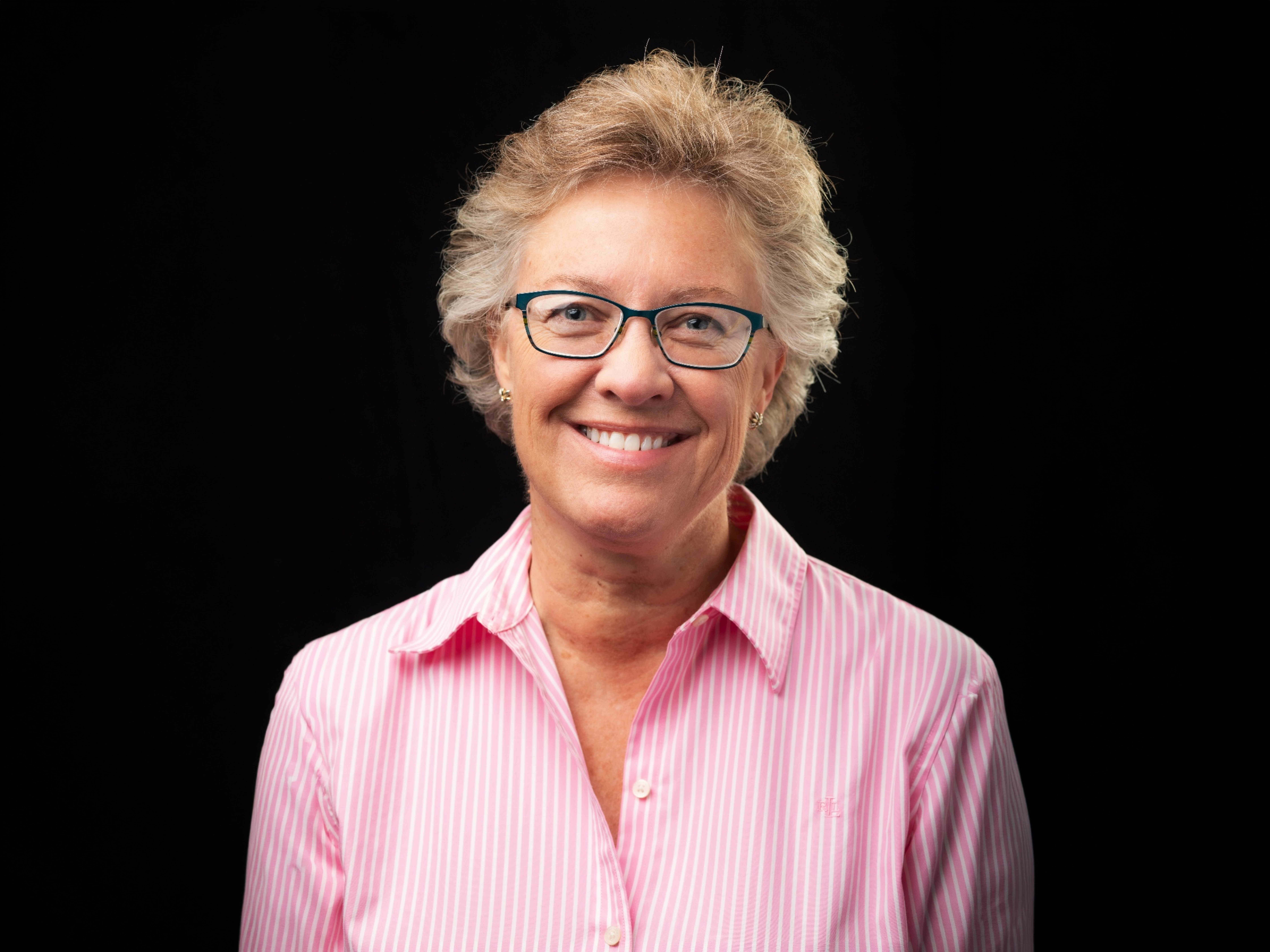 Headshot of Rev. Christina May, PhD, MPA, MDiv, in front of a black background. 
